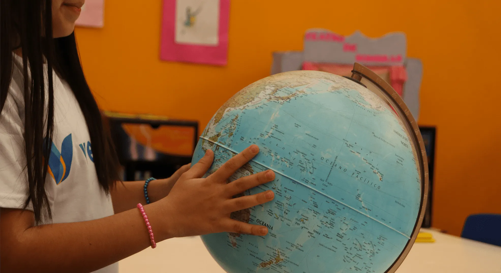 Aluna da Escola Vereda explorando o mundo com globo terrestre - Tour virtual disponível